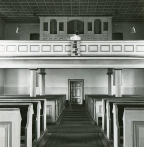 Kirche, Blick zur Orgel (mit Bänken im Kirchenschiff)