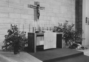 Kirche, Altartisch mit an der Wand hängendem Kruzifix